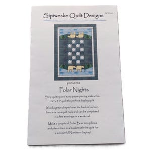 May include: A white paper quilt pattern titled Sipiweske Quilt Designs Polar Nights. The cover features a graphic of a 66 cm by 86 cm quilt with a blue and white checkerboard centre, dark blue borders, and illustrations of polar bears.