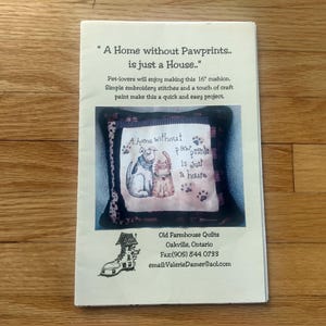 以下が含まれることがあります： 「A Home without Pawprints is just a House」というテキストが印刷されたページ。犬と猫のイラストが描かれた装飾用クッションが特徴です。クッションのサイズは約40cmです。