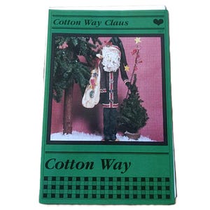 May include: A rectangular craft pattern envelope titled Cotton Way Claus with a green border and a black checkered pattern at the bottom. The central image shows a Santa figure with a white beard, a dark coat, and a sack standing near trees.