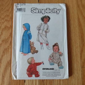 May include: A Simplicity sewing pattern envelope, number 8326, size 2. The white paper cover features illustrations of children wearing various outfits, including a blue hooded robe, a polka-dot dress, a red jumpsuit, and a patterned romper.