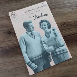 May include: A vintage knitting pattern booklet titled CANADIANA PULLOVERS by Beehive, featuring a blue-toned illustration of two people wearing V-neck sweaters with striped trim. The cover includes the text 25 CENTS and in 8 sizes.