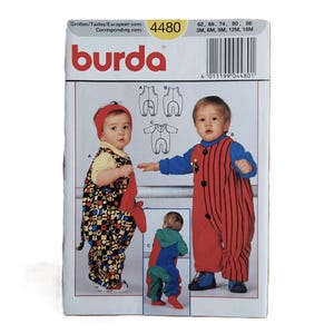 May include: A Burda sewing pattern envelope, number 4480, featuring illustrations of infants wearing various one-piece jumpsuits. The designs include a patterned jumpsuit with a hood, a red and blue color-blocked jumpsuit, and a red striped jumpsuit.
