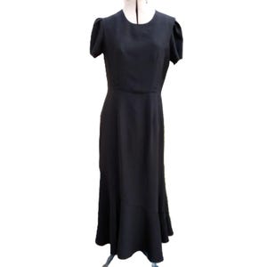 May include: A black dress with short, puffed sleeves and a fitted bodice. The dress has a flared skirt that falls to the floor. The dress is displayed on a dress form against a white background.