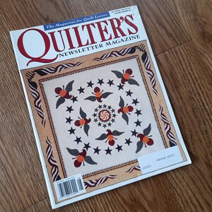 May include: A copy of Quilter's Newsletter Magazine from July/August 2005, issue 364. The cover features a cream-coloured quilt with a central star pattern, surrounded by dark blue stars and bird motifs, framed by a tan border with wavy red and white stripes.