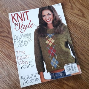 May include: A Knit 'N Style magazine issue from October 2005 featuring a Fall/Winter fashion forecast. The cover displays a person wearing a textured olive green sweater with a central argyle pattern in yellow, red, and blue diamonds.