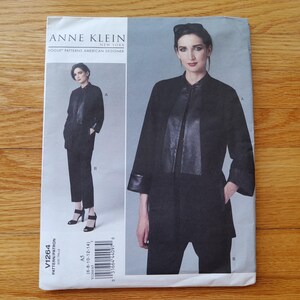 May include: An Anne Klein Vogue Patterns sewing pattern envelope for a jacket and trousers set. The cover features a black jacket with a central panel and cuffs, paired with black trousers. Text includes Anne Klein New York, Vogue Patterns, and V1264.