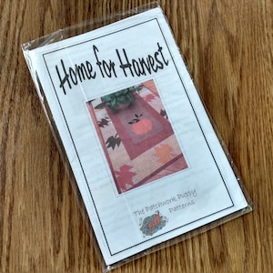 May include: A pattern packet titled "Home for Harvest" in a clear plastic sleeve. The cover features a quilt design with a pumpkin and autumn leaves. The text "The Patchwork Puppy Patterns" is also visible.