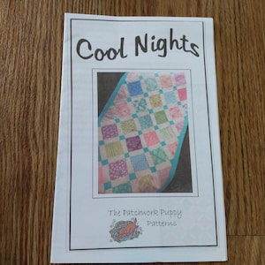May include: A printed pattern titled "Cool Nights" featuring a colourful patchwork quilt design. The pattern is from "The Patchwork Puppy Patterns." The quilt design includes squares in pastel colours like pink, blue, green, and yellow.