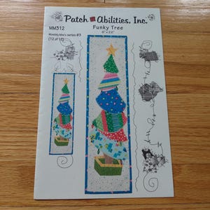 May include: A paper pattern for a Funky Tree quilt, 15 cm x 56 cm, by Patch Abilities, Inc. The design features a whimsical Christmas tree with colourful, stacked layers and a star on top. The pattern is part of the Monthly Mini's series #3.