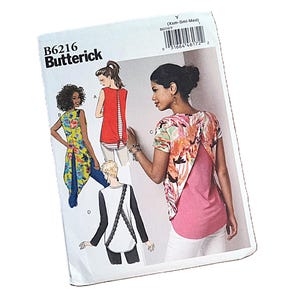 May include: A Butterick B6216 sewing pattern envelope featuring illustrations of four different top designs. The designs include sleeveless and short-sleeved shirts with varied back details, including open backs, floral prints, and lace trim accents.