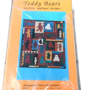 Peut inclure: Un livret de patrons intitulé Teddy Bears machine appliqué designs par Debora Konchinsky, numéro 9402, daté de 1994. La couverture présente une illustration de courtepointe avec divers motifs d'ours en peluche de couleurs rouge, bleu et blanc.