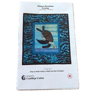 Peut inclure: Un livret de patron de courtepointe Kilauea Kreations Grazing avec une illustration de tortue marine dans une bordure à motifs bleus et noirs. La couverture affiche le texte Kilauea Kreations Grazing, 28 cm par 32 cm, et Designed by Castilleja Cotton.