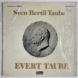 May include: A vintage vinyl record album titled "Sven Bertil Taube" and "Evert Taube." The album cover is off-white with gold lettering and a textured, circular image of a man's profile. The record is sealed in plastic.