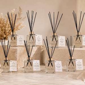 May include: Eight clear glass reed diffuser bottles with gold-tone collars and black reeds. Each bottle features a white label with the text Velvet House and a specific scent name, including Lychee & Peony, Eternal Rose, French Pear, and Blue Sage & Sea Salt.