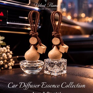 May include: Two car diffusers with brown braided hanging cords and light wood caps. One diffuser has a rounded glass base, while the other features a faceted, square-shaped glass base. Text reads Velvet Flame, Car Diffuser Essence Collection, Aura & Crystal.