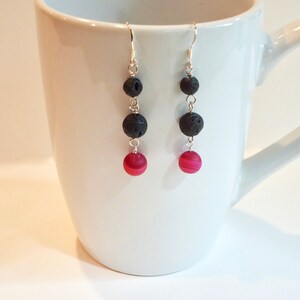 Peut inclure: Une paire de boucles d'oreilles pendantes avec trois perles de lave noire et une seule perle d'agate rose sur chaque boucle d'oreille.