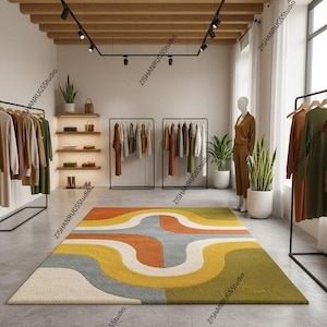 May include: A colorful, geometric rug with a retro design dominates the foreground of a clothing store. The rug features curved lines in shades of yellow, orange, green, and gray. Clothing racks and a mannequin are visible, suggesting a fashion retail setting.