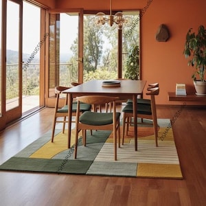 May include: A dining room scene featuring a wooden table and chairs set on a colorful geometric rug. The rug has green, yellow, and gray sections. The room has large windows and a warm, inviting color scheme.
