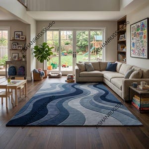 May include: A large blue rug with a wave design in a living room. The rug features shades of blue and grey, creating a flowing pattern. The room includes a beige corner sofa, wooden flooring, and a view of a garden.
