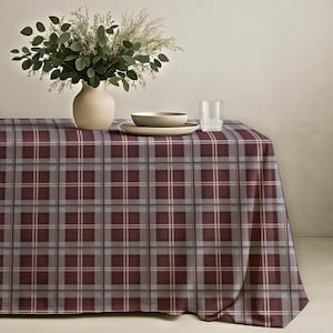 Könnte beinhalten: Ein bordeaux- und grau kariertes Tischtuch bedeckt einen Tisch mit einer Vase mit Grün, einer Schüssel, einem Teller und einem Glas Wasser. Das Tischtuch hat ein klassisches Karomuster in Bordeaux, Grau und Creme. Die Tischdekoration ist schlicht und elegant.