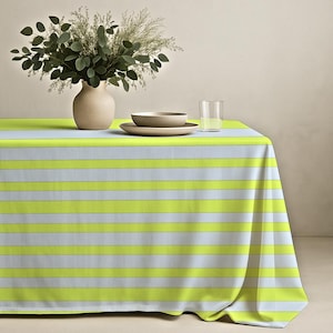 May include: A rectangular tablecloth featuring horizontal stripes in alternating shades of bright lime green and light gray. The fabric drapes over the edges of a table, displaying a consistent pattern across the entire surface of the textile.