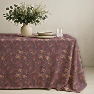 May include: A rectangular tablecloth featuring a repeating pattern of stylised thistle-like flowers in shades of deep plum, muted pink, and soft orange on a dark purple background, draped over a table with a ceramic vase and dishware.