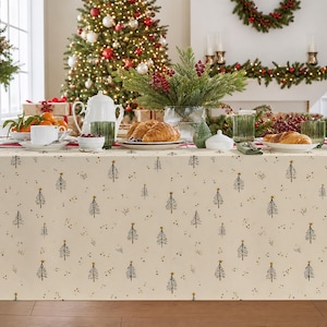May include: A cream-coloured tablecloth featuring a repeating pattern of black line-drawn Christmas trees topped with small gold stars, interspersed with scattered black dots. The fabric covers a table set for a holiday meal with various dishes.