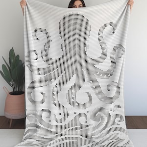 May include: White blanket featuring a black octopus design. The octopus is created using a dot pattern, with its tentacles and head prominently displayed. The blanket has a decorative wave pattern at the bottom.