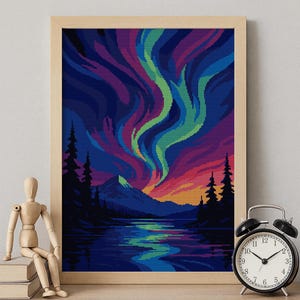 May include: A framed pixel art print depicting the aurora borealis over a mountain and lake. The artwork features vibrant colors of blue, purple, green, and orange. A wooden artist's mannequin and a black alarm clock are on the shelf.