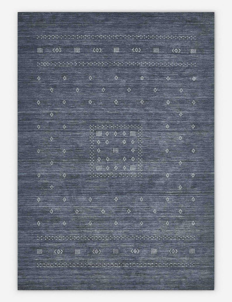 May include: A rectangular, indigo blue area rug with a geometric pattern. The rug features rows of white diamond and rectangular shapes, along with dotted lines and decorative symbols. The central design is a square with a grid of white dots.