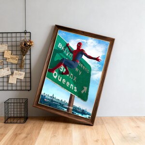 May include: Framed artwork featuring Spider-Man on a green highway sign pointing towards Brooklyn, Bronx, and Queens. The poster has a cityscape background and the words "COMING SOON" at the bottom. The frame is a dark wood color.