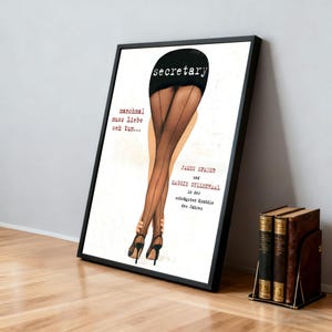 Può includere: Poster incorniciato con una pubblicità cinematografica vintage di "Secretary". L'opera raffigura le gambe di una donna con calze nere e tacchi alti. Il testo include il titolo del film e i nomi degli attori. Un fermalibri con libri è in primo piano.