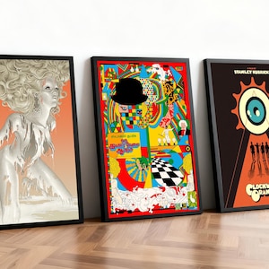 May include: Three framed posters with black frames, leaning against a white wall, showcasing artwork from "A Clockwork Orange." The posters display colourful, stylized illustrations. One features a woman, another a bowler hat, and all bear the film's title.