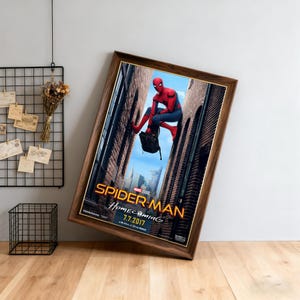 May include: Framed movie poster for Spider-Man: Homecoming, featuring the superhero in a red and blue suit. The poster has a brown wooden frame and the title is in gold lettering. The release date is July 7, 2017.