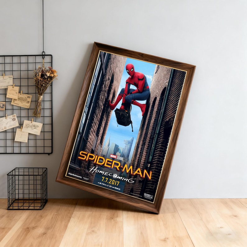 May include: Framed movie poster for Spider-Man: Homecoming, featuring the superhero in a red and blue suit. The poster has a brown wooden frame and the title is in gold lettering. The release date is July 7, 2017.