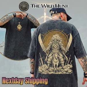 May include: Dark gray t-shirt featuring a gold and brown graphic of a warrior with two swords and a horse. The shirt also has the text "The Wild Hunt" and a logo. The front of the shirt has a gold design.