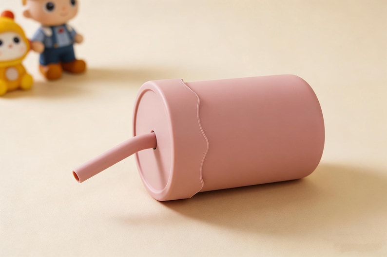 May include: A pink sippy cup with a matching straw. The cup has a wavy design around the lid. Two small figurines are in the background.