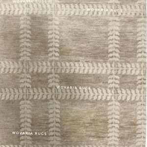 May include: Beige area rug with a plaid pattern. The rug features a grid design with vertical and horizontal lines, and leaf-like patterns. The text "WOVARIA RUGS" is printed in white across the top and bottom of the rug.