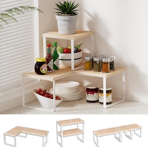 May include: A three-tiered corner shelf unit with a light wood finish and white metal frame. The shelves are filled with various kitchen items, including spices, sauces, and a potted plant. Additional shelf configurations are shown below.