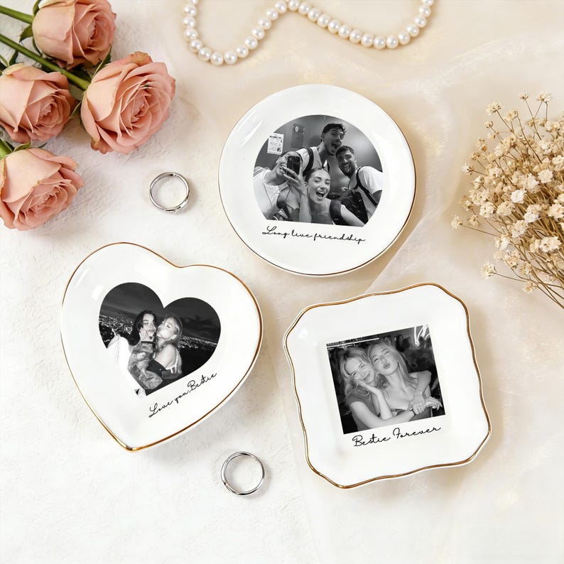 May include: Three white ceramic trinket dishes with gold trim, each featuring a black and white photo. One is round, one heart-shaped, and one square. The round dish says "Long line friendship." The heart dish says "Love you Bestie." The square dish says "Bestie Forever."