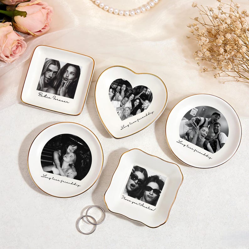 May include: A collection of white ceramic trinket dishes in various shapes, each featuring a black and white photograph and gold trim. The dishes include square, heart, and round shapes, with handwritten text such as "Bestie Forever" and "Long live friendship."