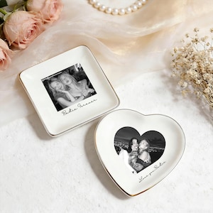 May include: Two decorative trinket dishes. One square dish and one heart-shaped dish. Both are white with gold trim and feature black and white photos. The square dish has the text "Bestie Forever". The heart dish has the text "Love you Bestie".
