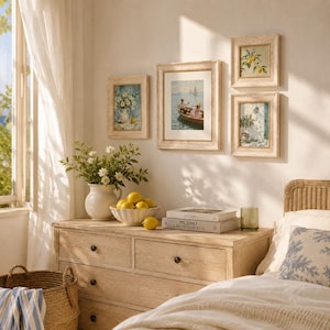 May include: A bedroom interior featuring framed artwork, a wooden chest of drawers, and a wicker basket. The art depicts floral arrangements, a boating scene, and lemons. A white vase holds flowers, and a bowl of lemons sits on the chest.