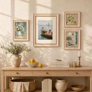 May include: A collection of framed art and decorative items on a wooden console table. The art features paintings of flowers, a boat scene, and lemons. A vase with foliage, a bowl of lemons, and books complete the display.