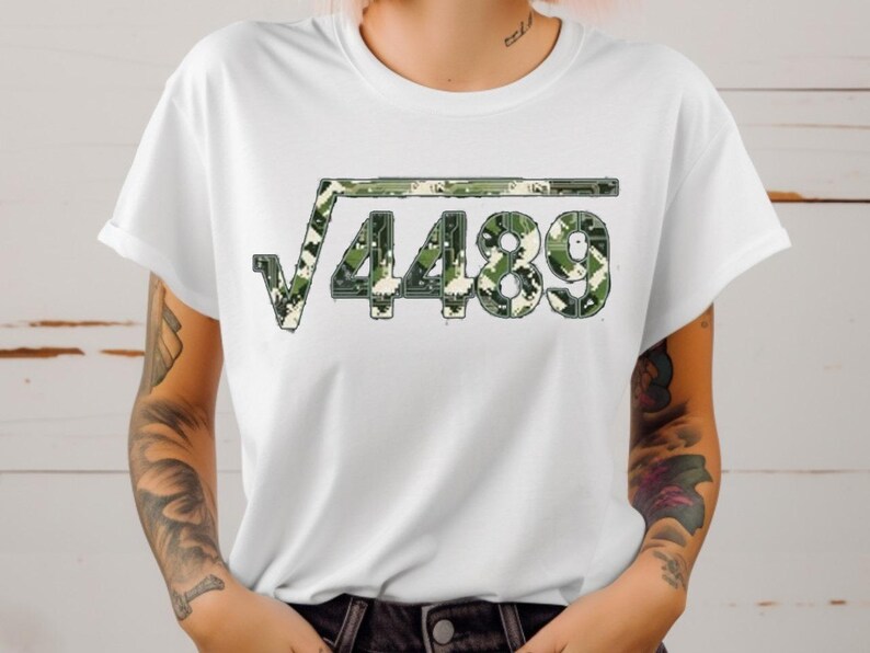 May include: White t-shirt with a square root symbol above the number 4489. The graphic is a camouflage pattern in green, brown, and beige. The shirt has short sleeves and a round neck.