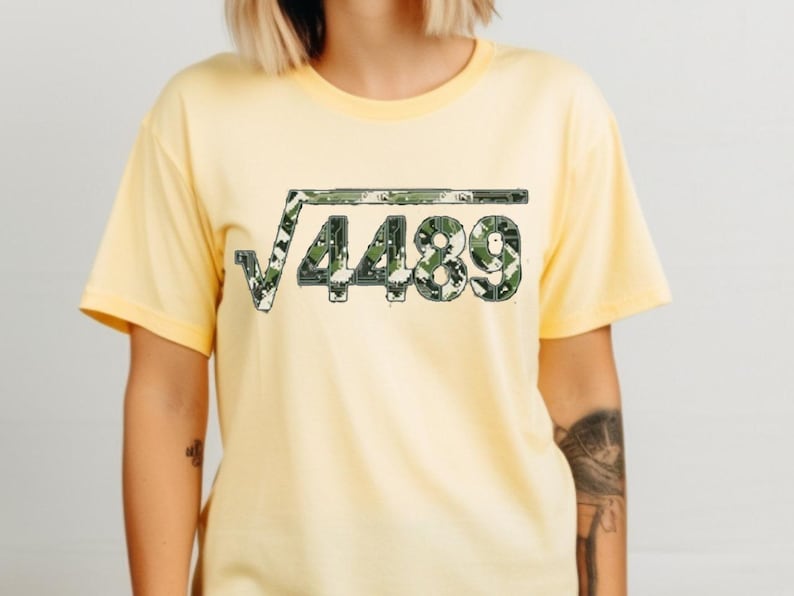 May include: A pale yellow t-shirt with a square root symbol and the number 4489 in a green and white camouflage design. The shirt has short sleeves and a round neck.