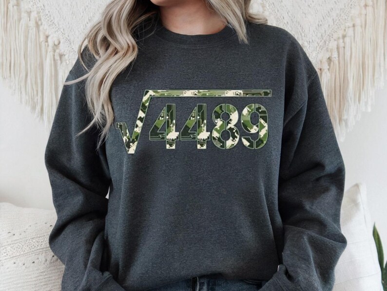 May include: Dark grey sweatshirt with a square root symbol and the number 4489 in a camouflage design. The pattern uses green, white, and tan. The sweatshirt is a casual garment.