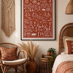 Op de afbeelding: Een ingelijste rechthoekige wandkunstprint met gedetailleerde witte lijnillustraties op een terracotta achtergrond, die een landelijk dorpstafereel toont met figuren, dieren, boten en bomen, omsloten door een decoratieve geometrische rand.