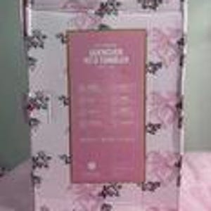 May include: A rectangular box with a pink and white floral pattern. The box has a pink label with text that reads "Lavender Bath & Body Collection". The box is white with a handle at the top.