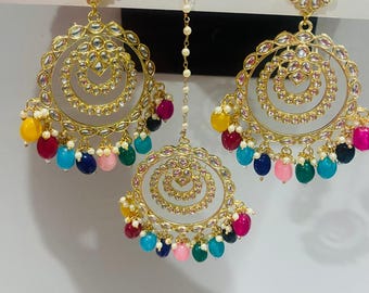 May include: Gold-coloured, ornate earrings and a headpiece with a spiral design and colourful beaded accents. The earrings have a floral top and a circular design with clear stones. The headpiece is connected to the earrings with a delicate chain.